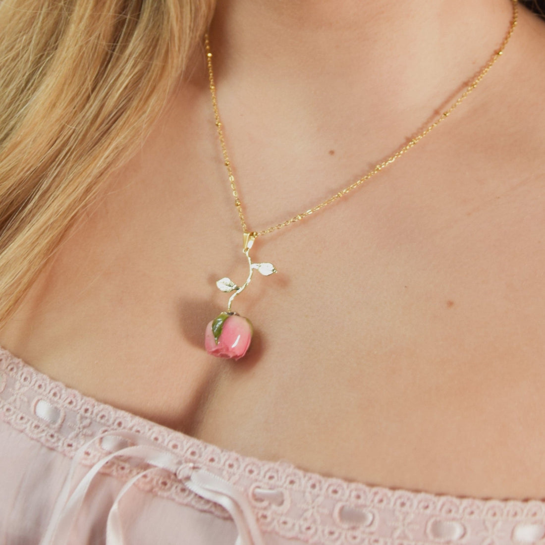 Handmade real rose dangle necklace with gold chain worn on a woman's neck.