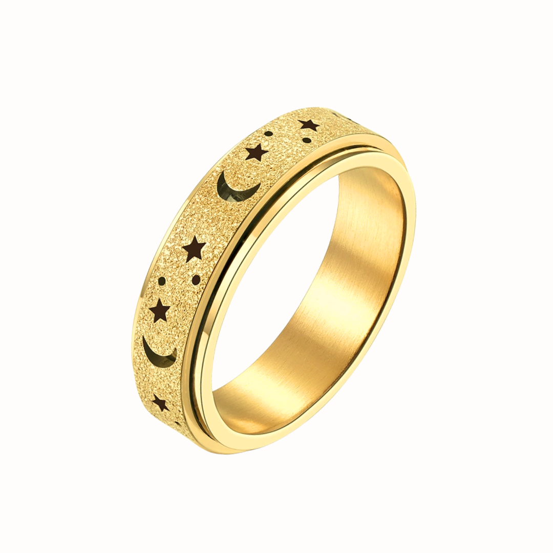 A gold-toned stainless steel spinner ring with star and moon engravings, photographed on a clean white background.
