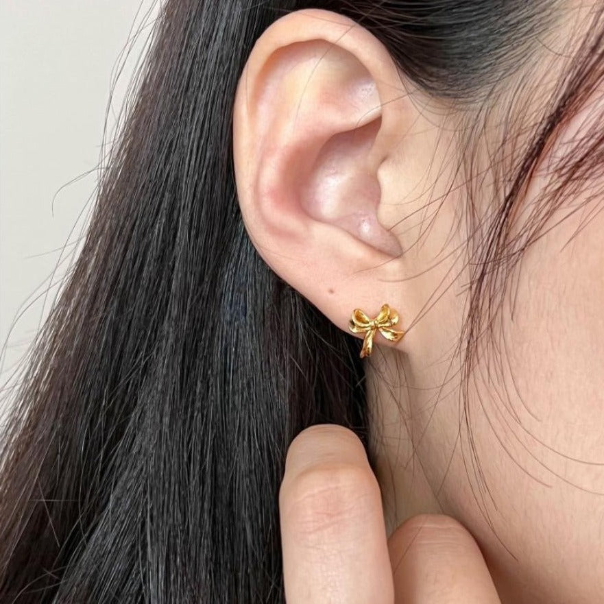 Close-up of dainty sterling silver bow stud earrings.