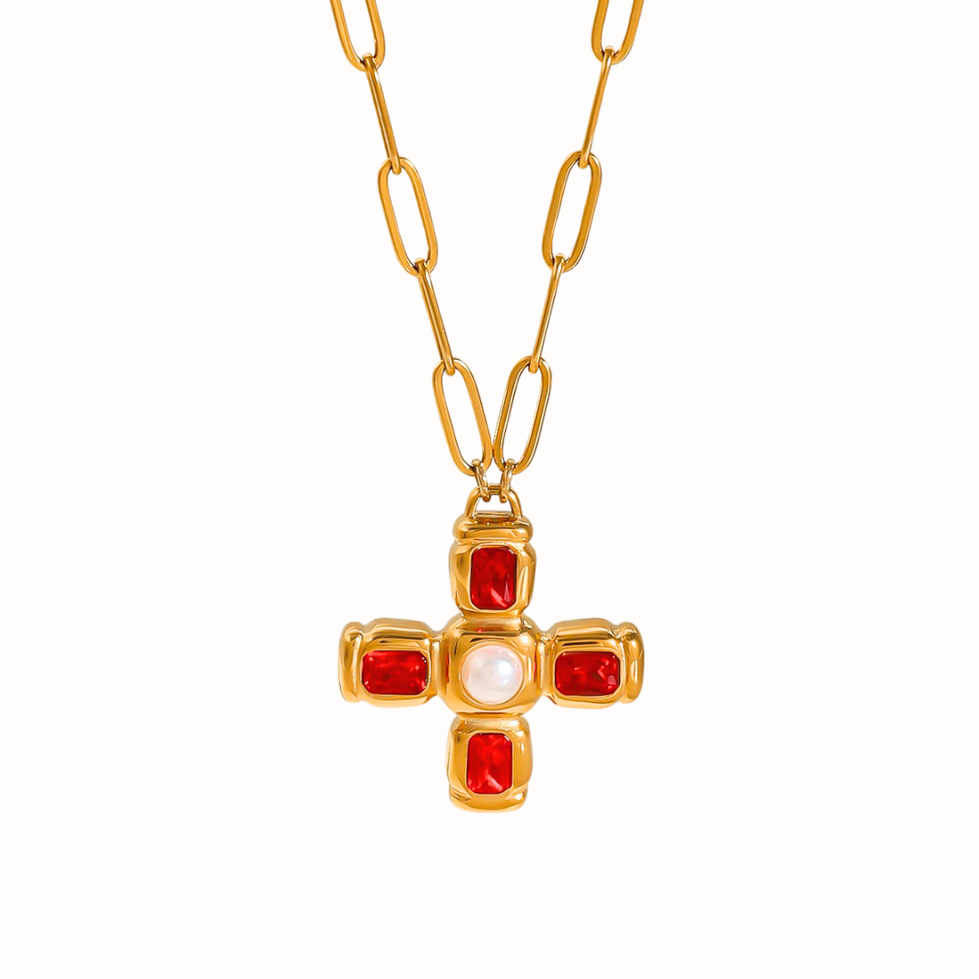 A gold stainless steel cross necklace with four deep red cubic zirconia stones and a luminous faux pearl in the center, shown on a clean white background.