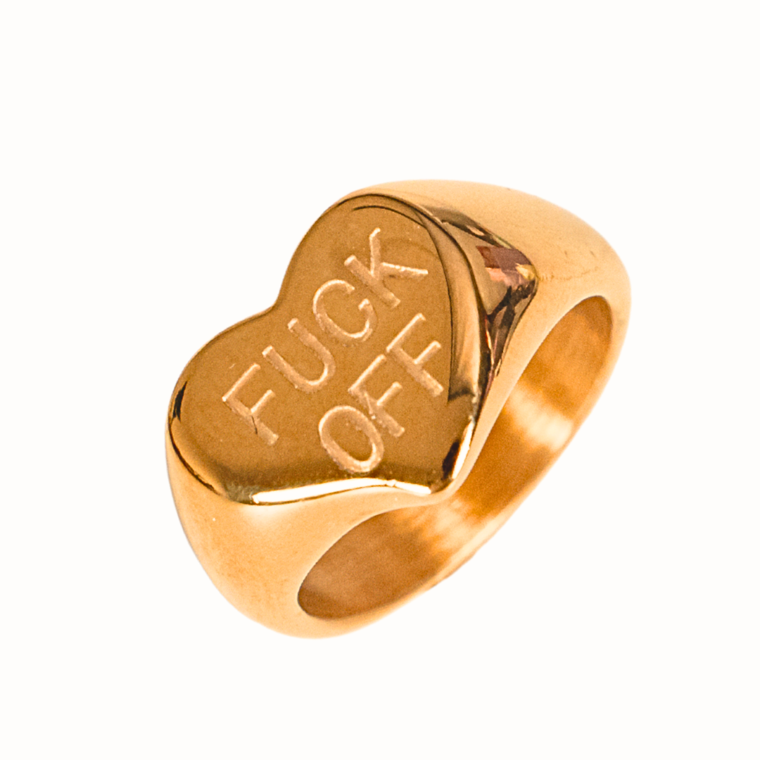 A bold gold asymmetrical heart ring engraved with “FUCK OFF".