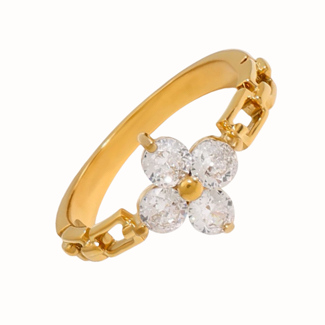 Gold stainless steel ring featuring an open chain-link band and a cubic zirconia flower centerpiece, photographed on a bright white background.