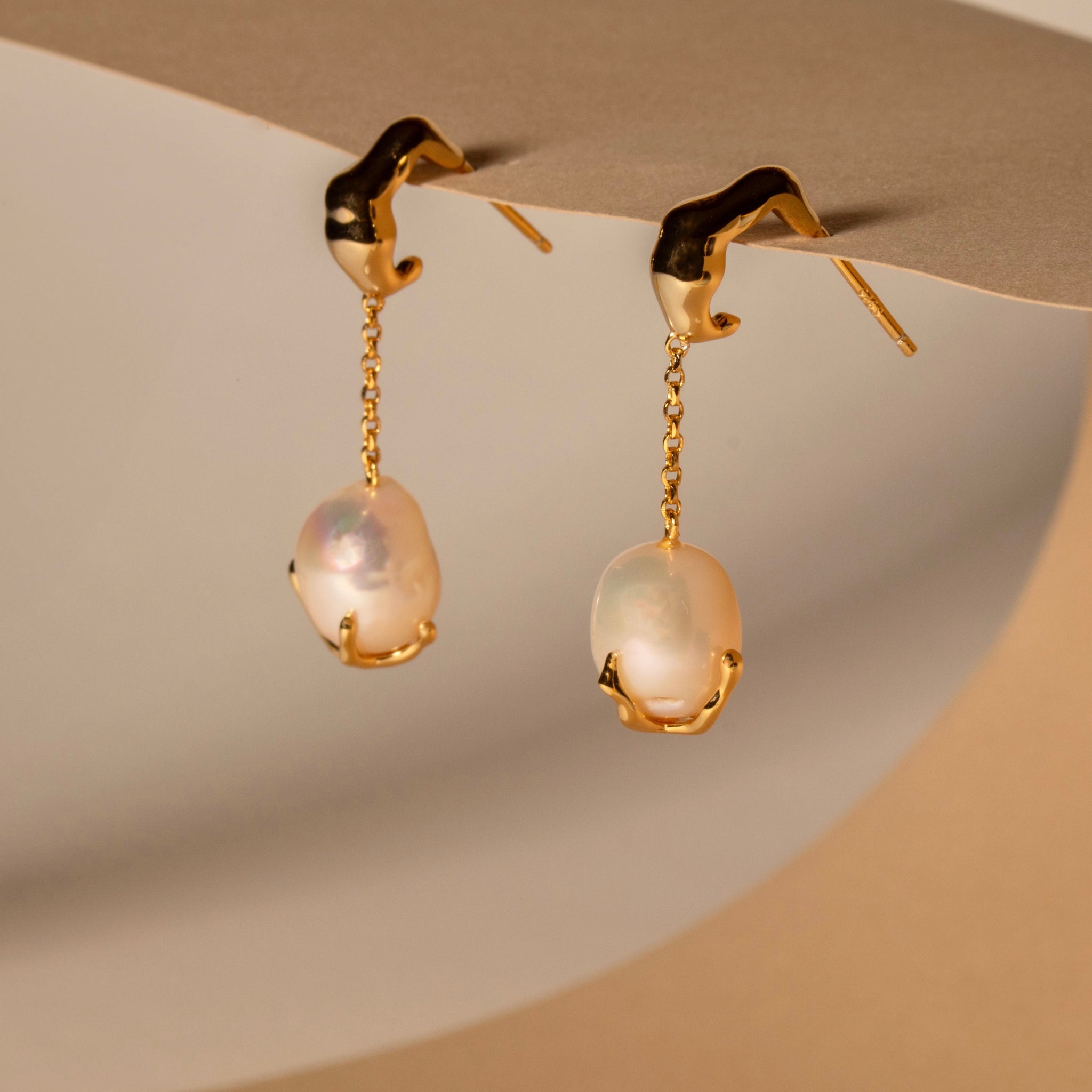 Close-up of golden baroque pearl drop earrings made from 18ct gold-plated sterling silver.