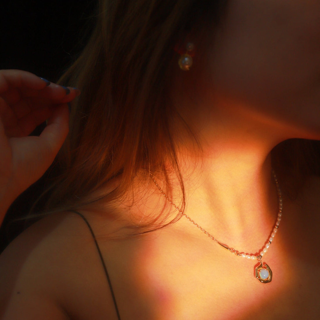 Delicate necklace with opal moonstone and freshwater pearls on a gold chain, styled as a choker.