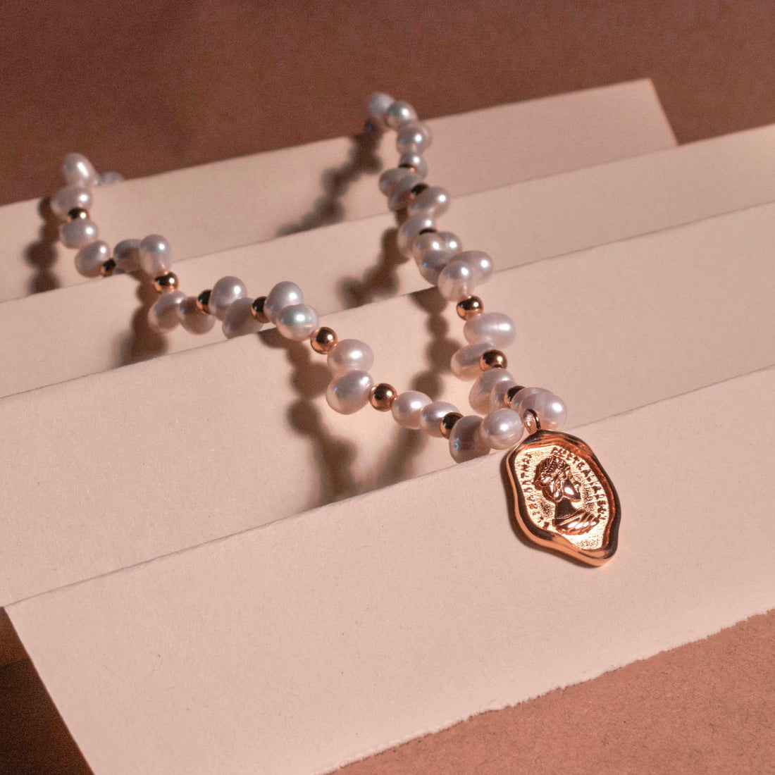 Freshwater pearl choker with queen portrait pendant in gold.
