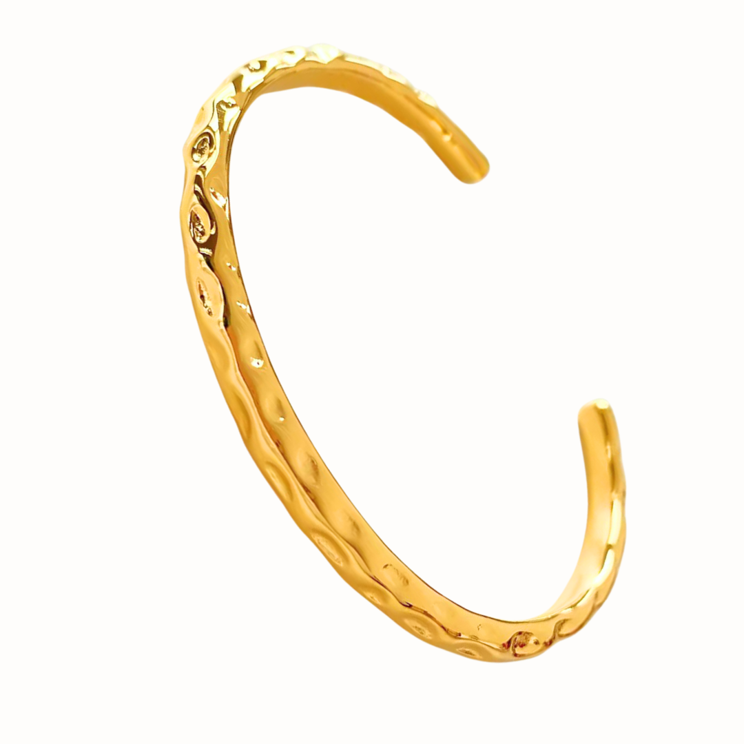 A textured stainless steel cuff bangle in gold displayed.