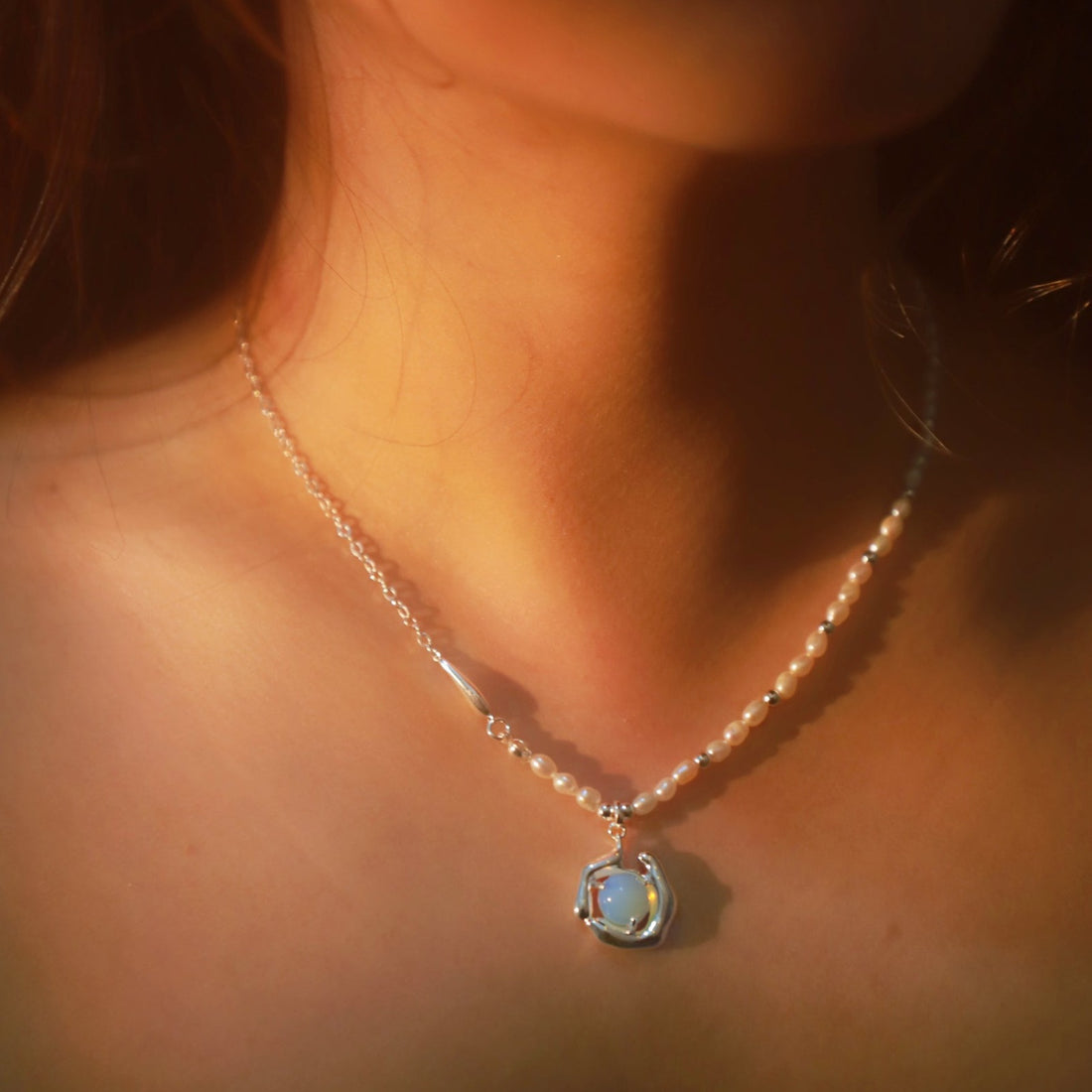 Delicate necklace with opal moonstone and freshwater pearls on a gold chain, styled as a choker.